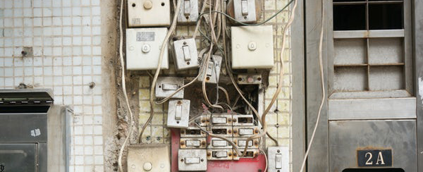 Tablero eléctrico con interruptores y cables enredados en la pared de la entrada de un edificio